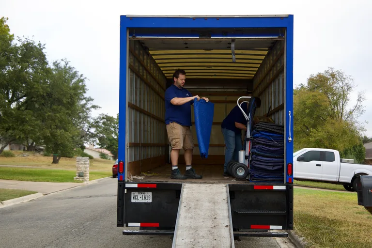 Looking into the rear of the RiverHills box truck as a mover folds moving blankets