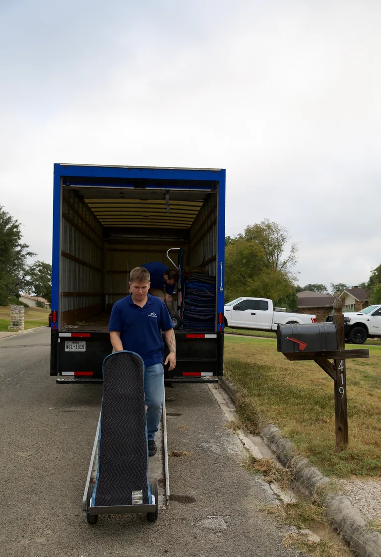 A RiverHills crew member wheeling a padded, shrink-wrapped item on a dolly
